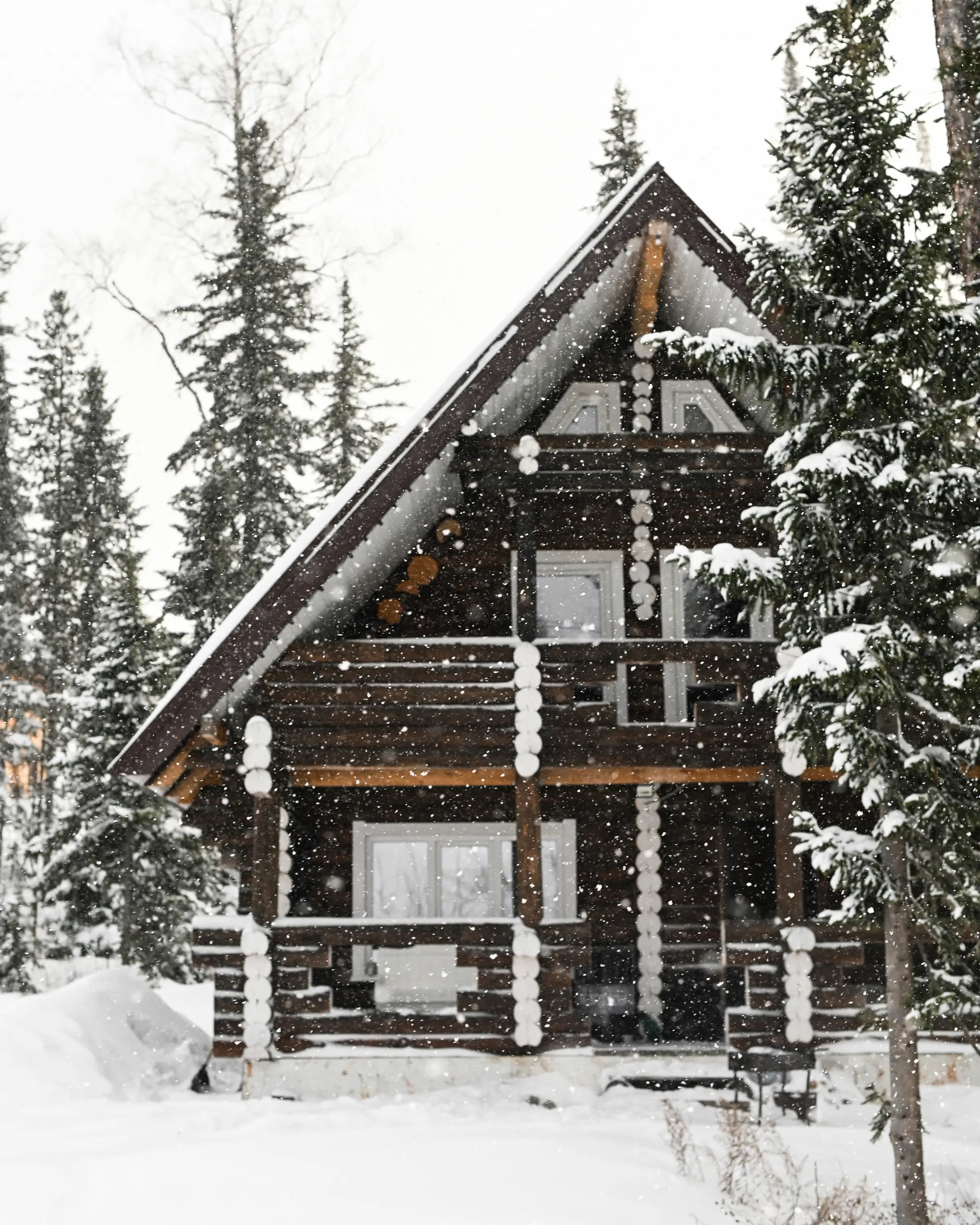 A timber mountain home in falling snow among the pines